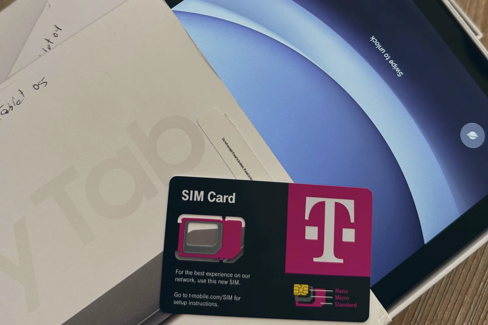 Tablets in their packaging with a T-Mobile SIM card resting on top and a handwritten label reading Tablet 05
