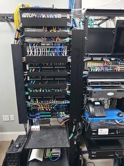 The same rack after remediation, with cables terminated onto stacked patch panels and routed through vertical cable management