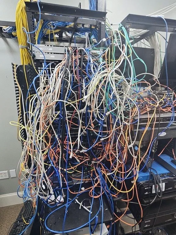 Equipment rack with several hundred unlabelled patch cables hanging loose across the front of the switches